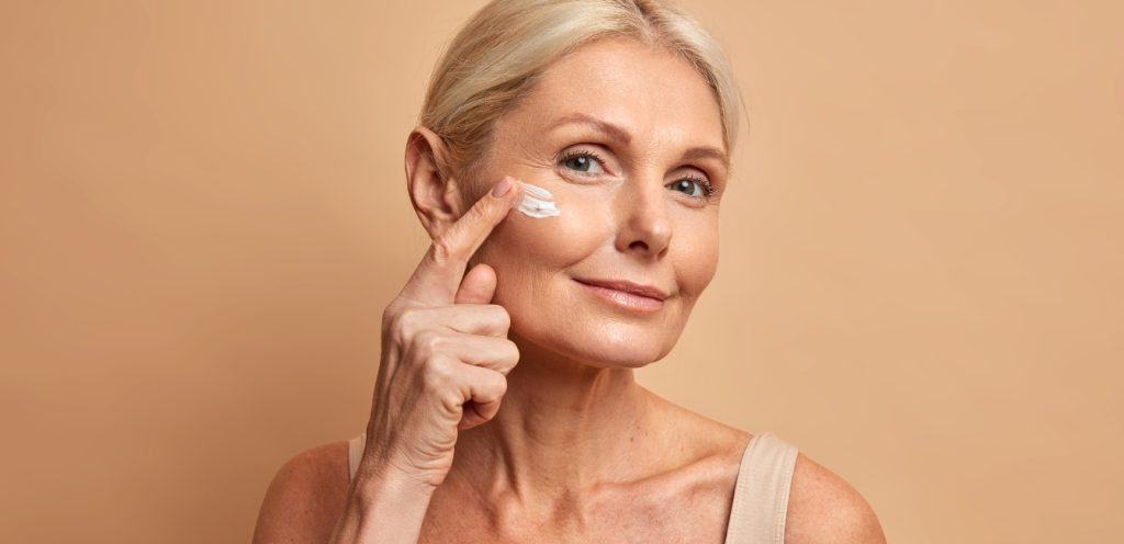 Copy of middle aged beautiful woman applies anti aging cream face undergoes beauty treatments cares about skin 1