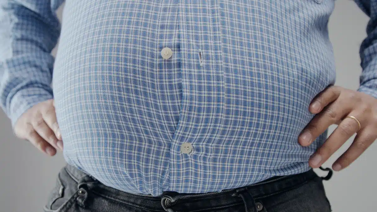 Overweight man in shrt is small to him with huge belly and open buttons