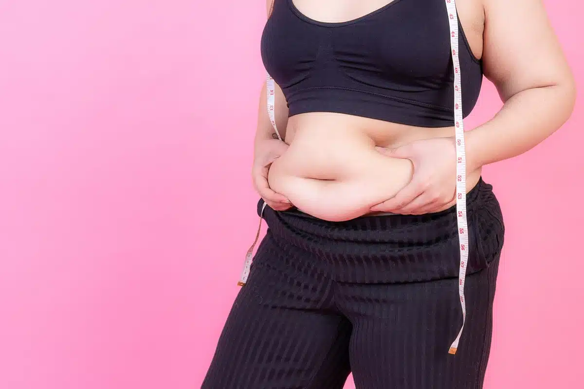 Overweight squeeze belly fat with measure tape on her neck